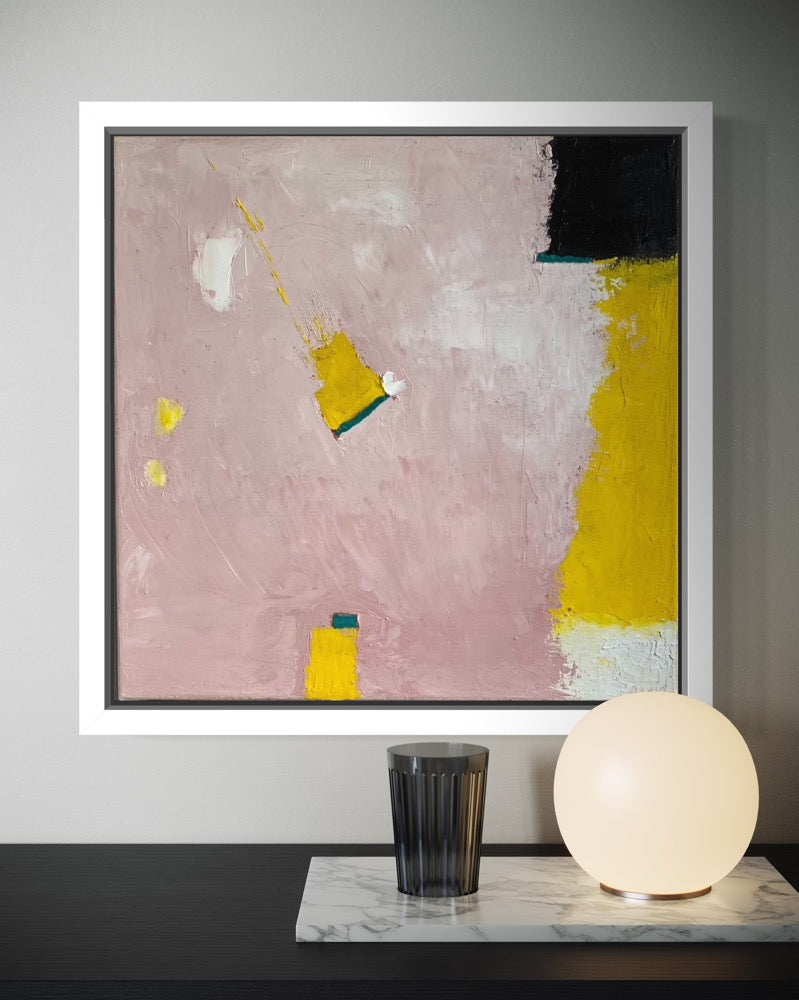 Abstract painting with pink, yellow, and black on a wall above a table with a lamp and glass.
