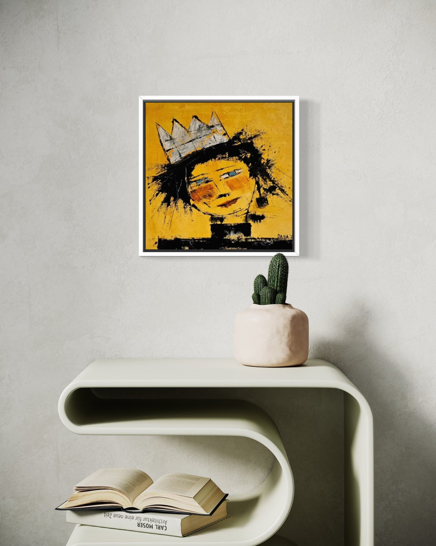 Dalla myndlist, Untitled. Framed abstract artwork of a face with a crown on a wall above a white console table with books and a cactus.