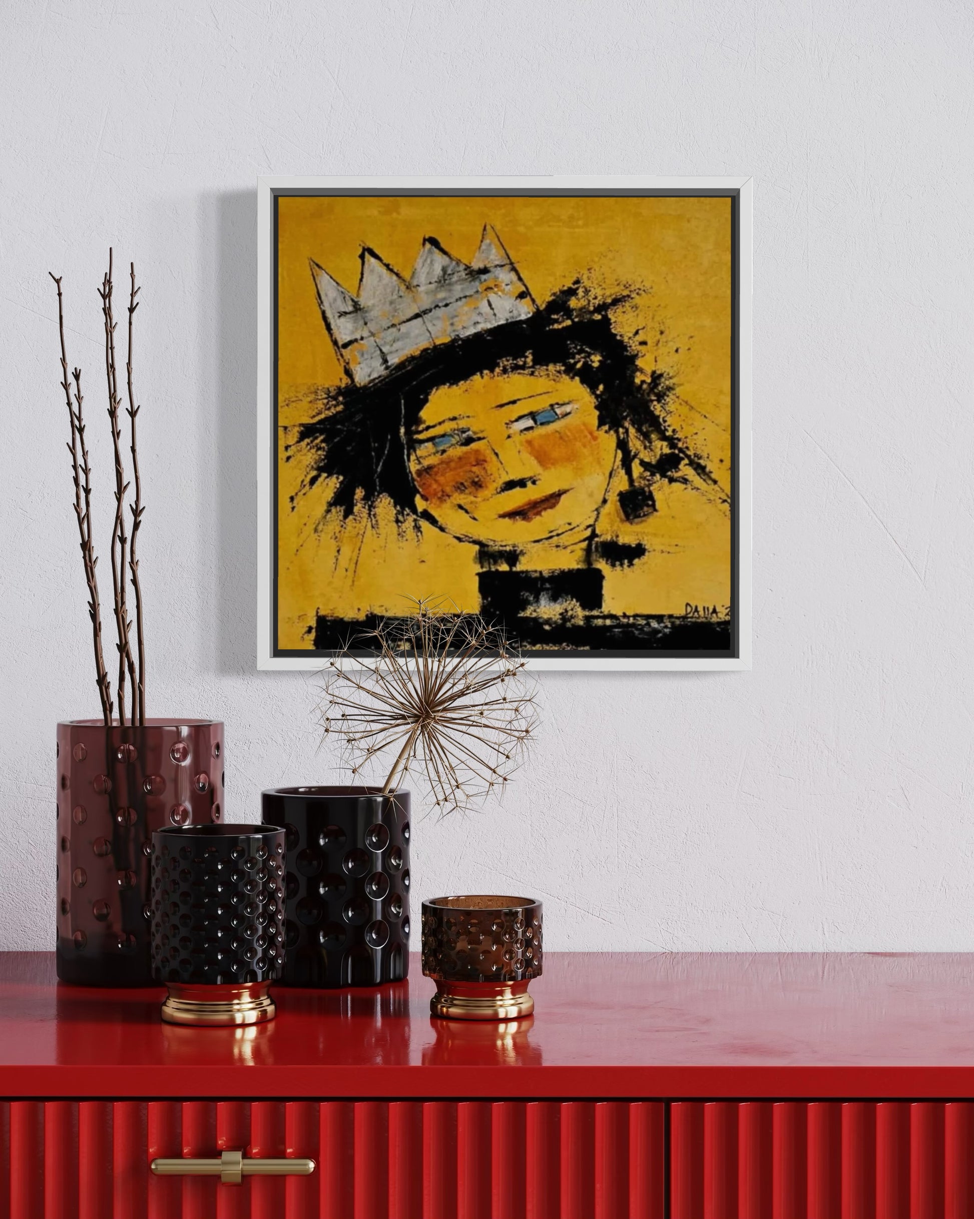 Dalla myndlist, Untitled. Framed artwork of a stylized face with a crown on a yellow background, displayed above a red cabinet with decorative items.