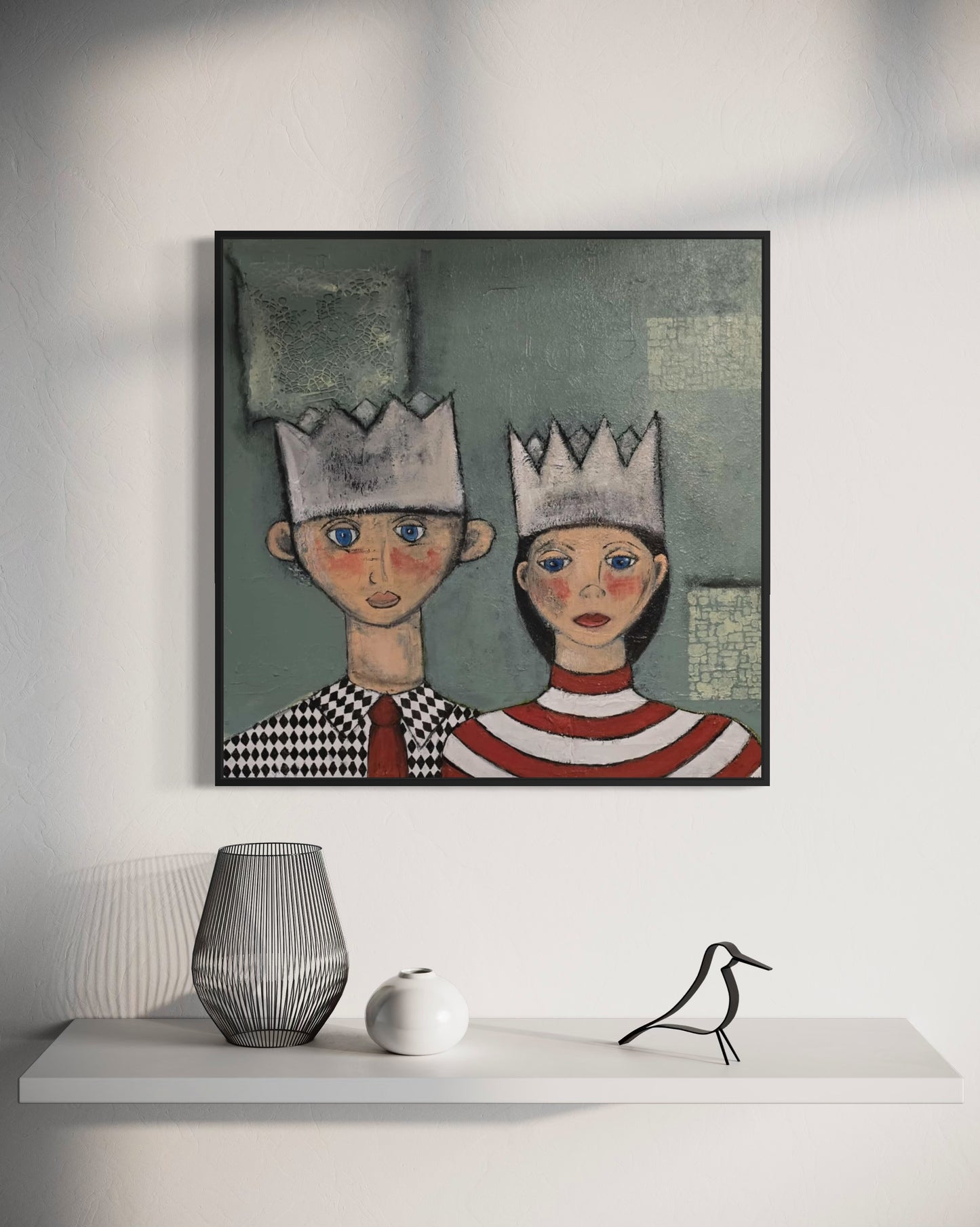 Dalla, Untitled. Framed acrylic artwork of two people wearing crowns on a white wall above a shelf with decorative items.